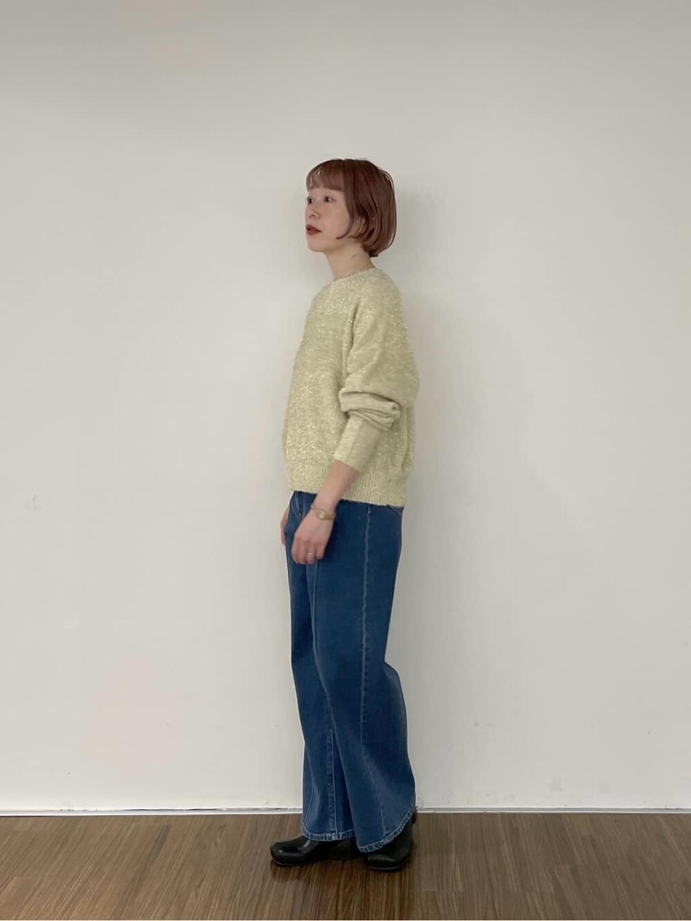 ブルー系のデニムパンツ、ゴールド系のニット/セーターを着用したレディースの秋コーディネートの2枚目の写真