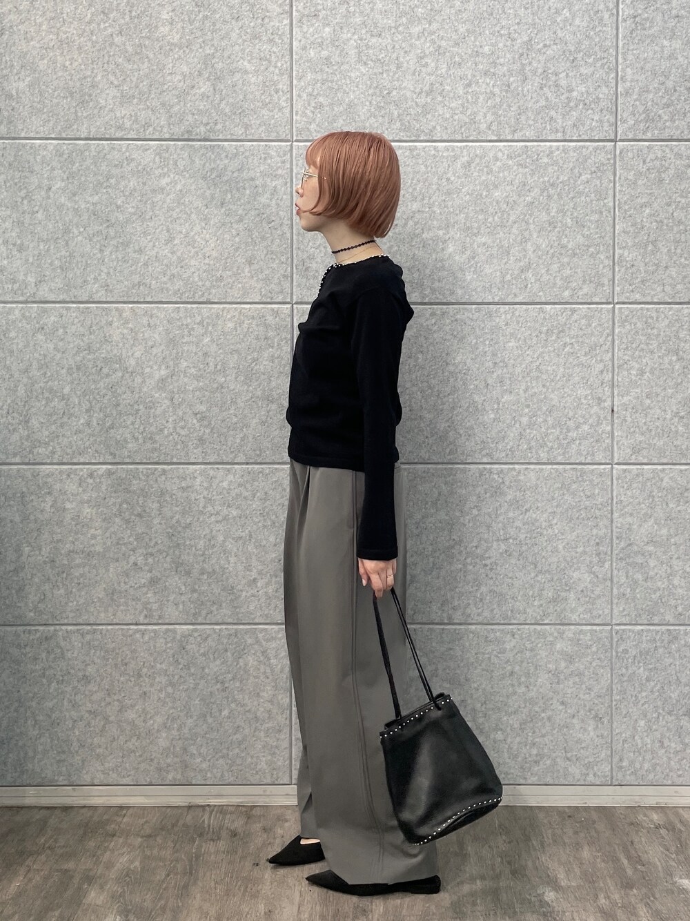 グレー系のその他パンツ、シルバー系のハンドバッグ、ブラック系のニット/セーターを着用したレディースの夏コーディネートの2枚目の写真