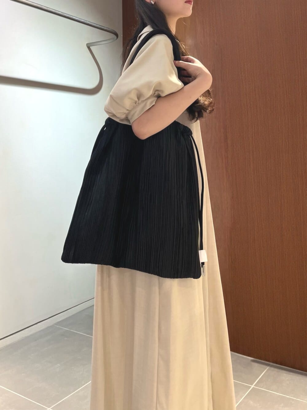 シルバー系のパンプス、ベージュ系のワンピース、ブラック系のトートバッグを着用したレディースの夏コーディネートの5枚目の写真