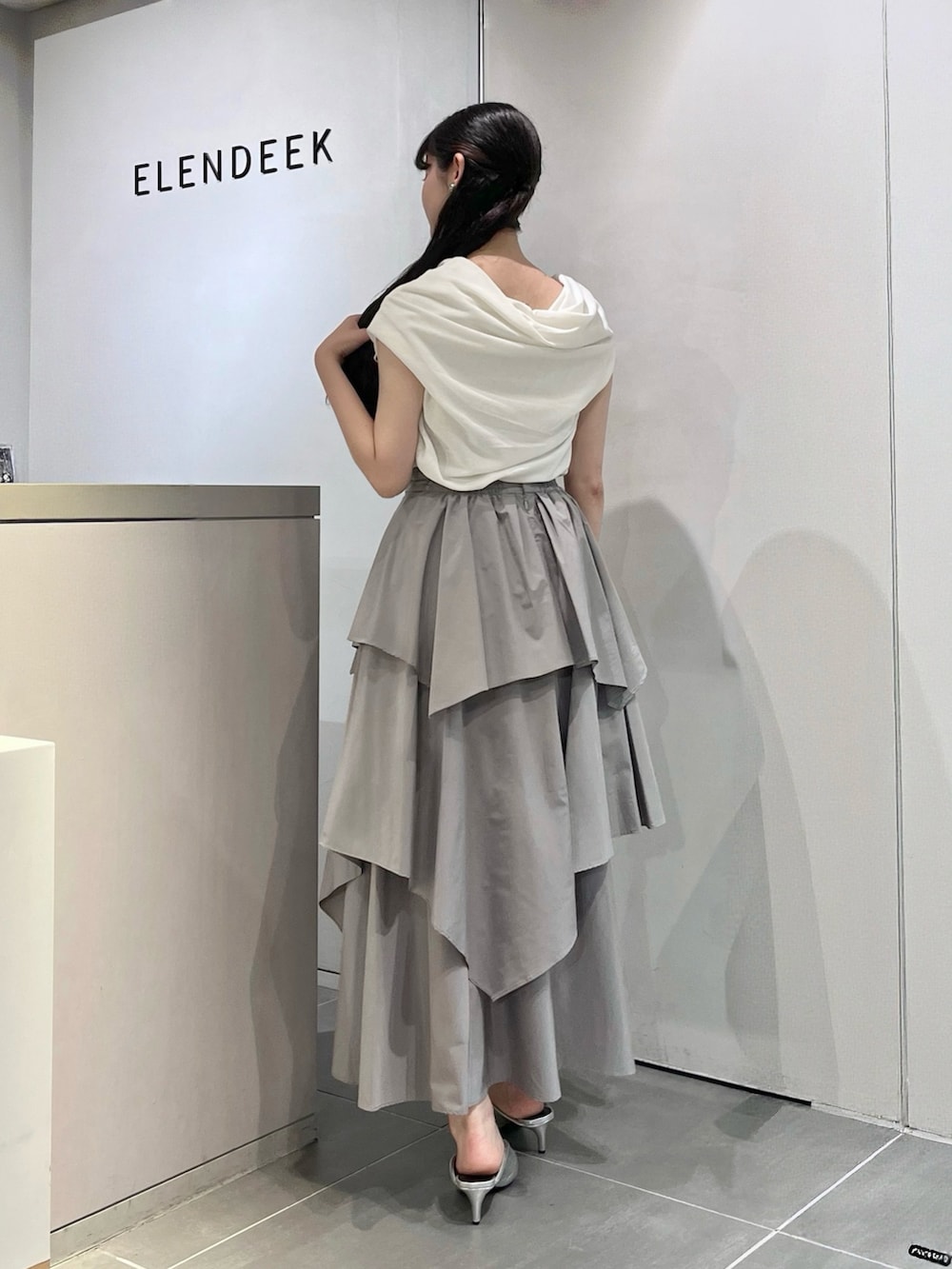 ホワイト系のTシャツ/カットソー、グレー系のスカート、シルバー系のパンプスを着用したレディースの夏コーディネートの3枚目の写真