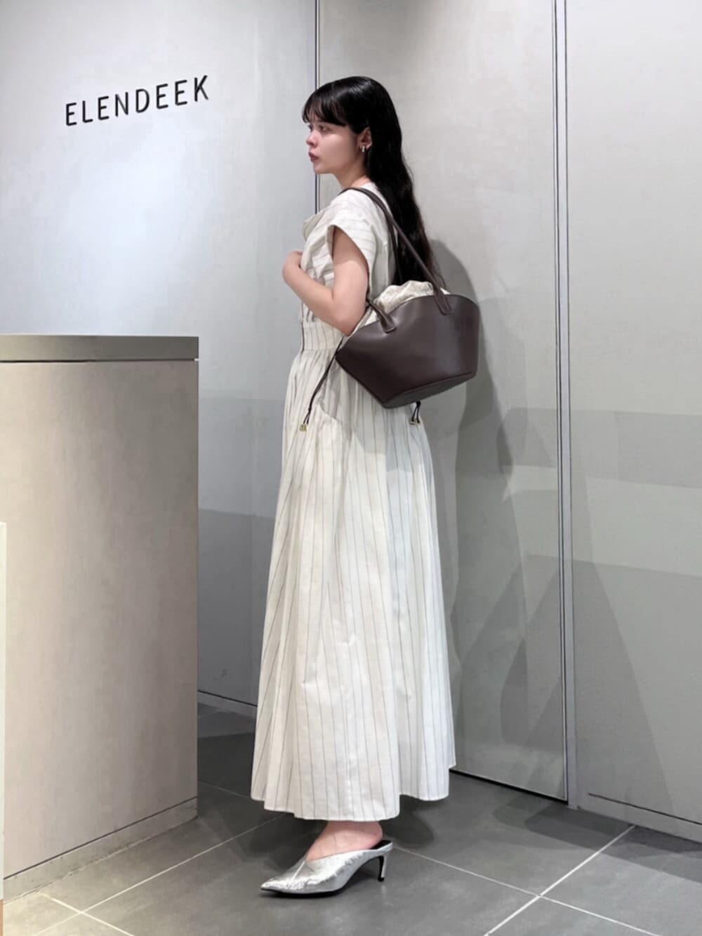シルバー系のパンプス、ブラウン系のトートバッグ、その他のワンピースを着用したレディースの夏コーディネートの4枚目の写真