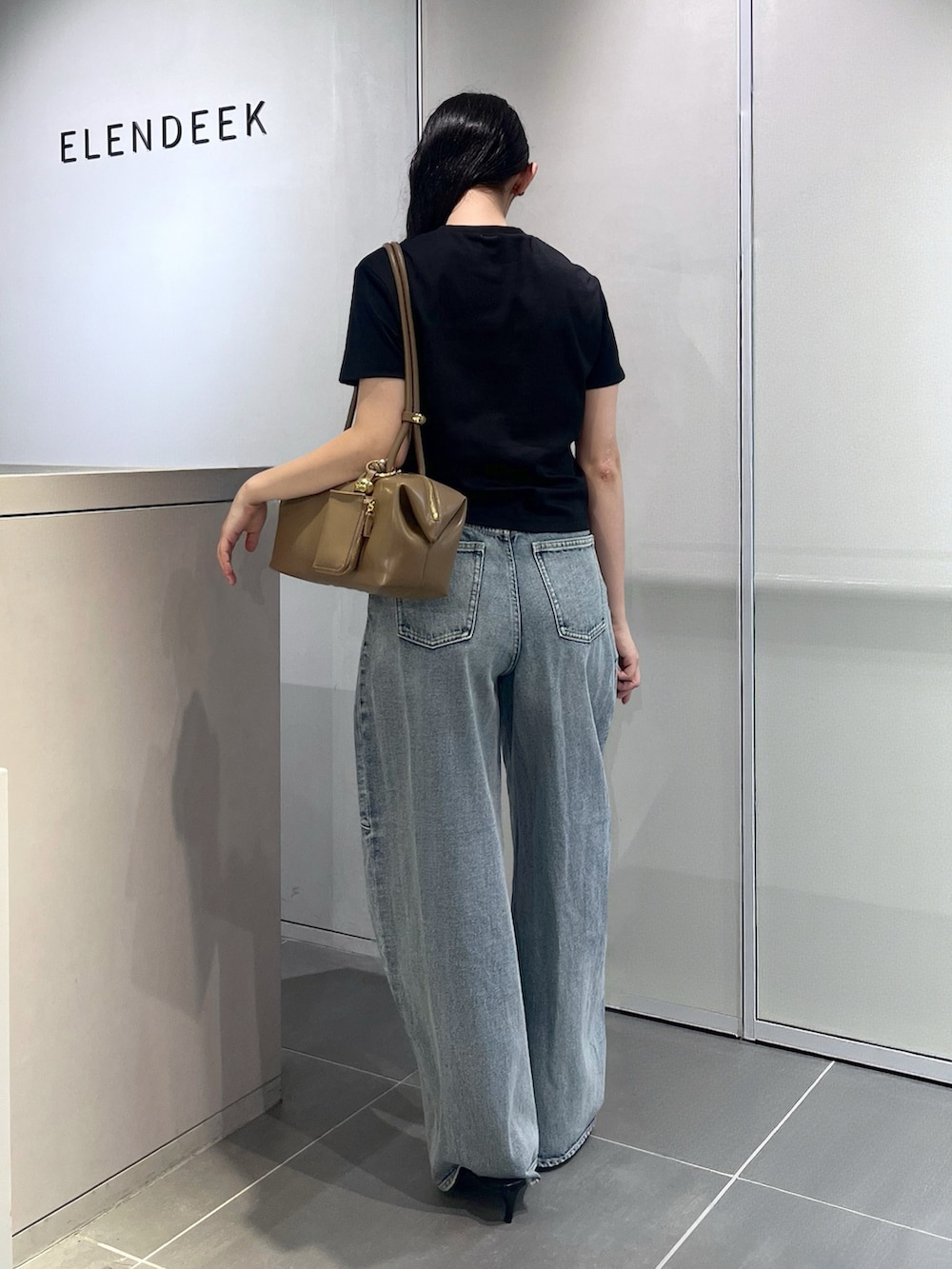 ブラック系のTシャツ/カットソー、ブルー系のデニムパンツ、ブラウン系のボストンバッグを着用したレディースの夏コーディネートの3枚目の写真
