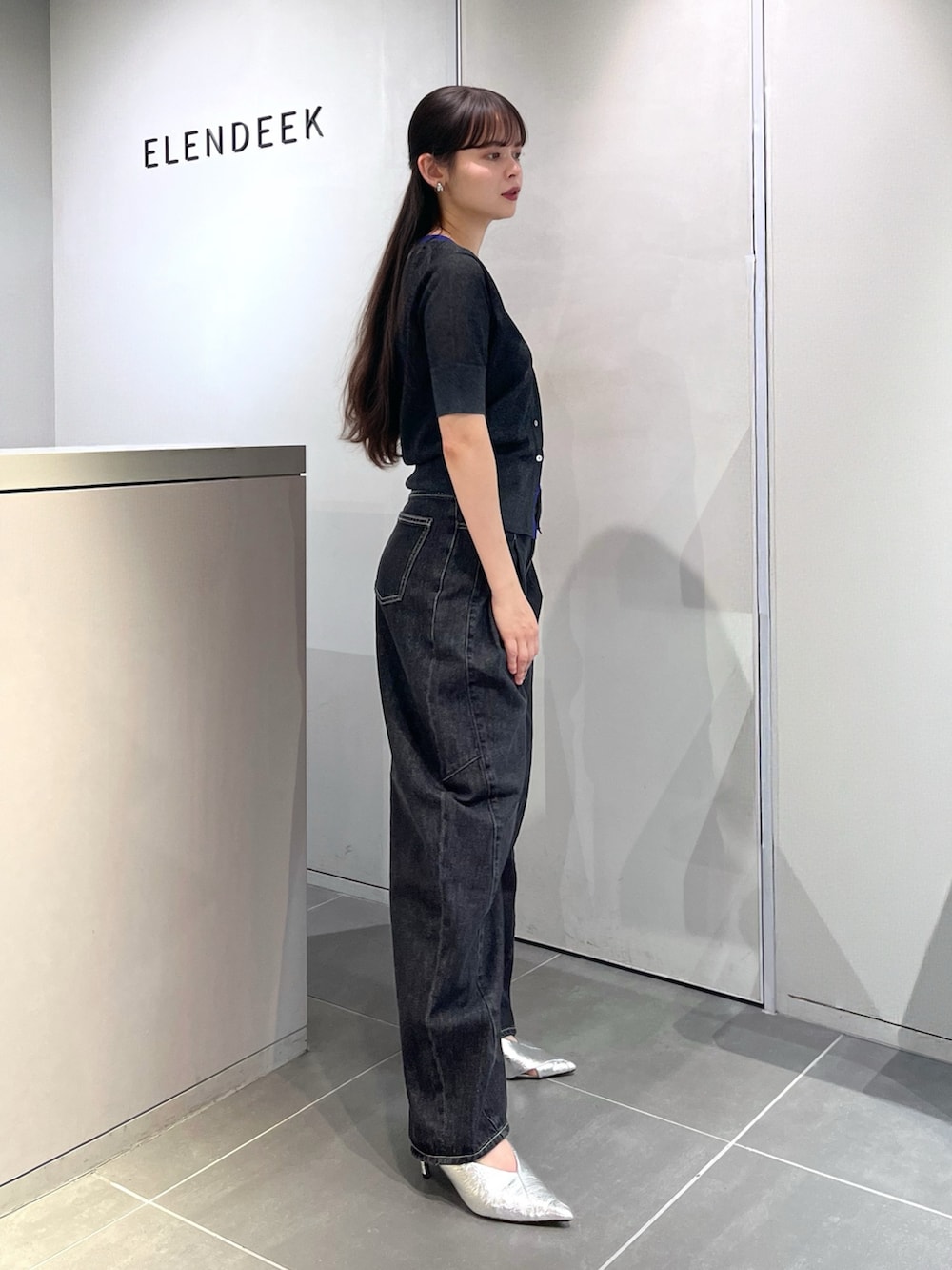グレー系のニット/セーター、ブラック系のデニムパンツ、シルバー系のパンプスを着用したレディースの夏コーディネートの2枚目の写真