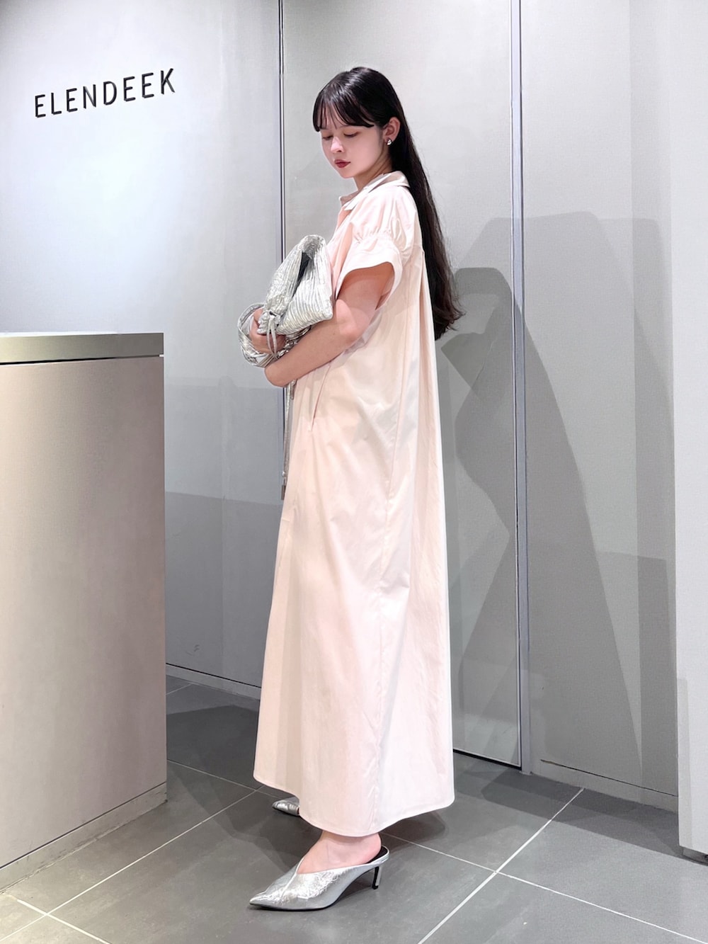 シルバー系のトートバッグ、シルバー系のパンプス、ピンク系のワンピースを着用したレディースの夏コーディネートの4枚目の写真