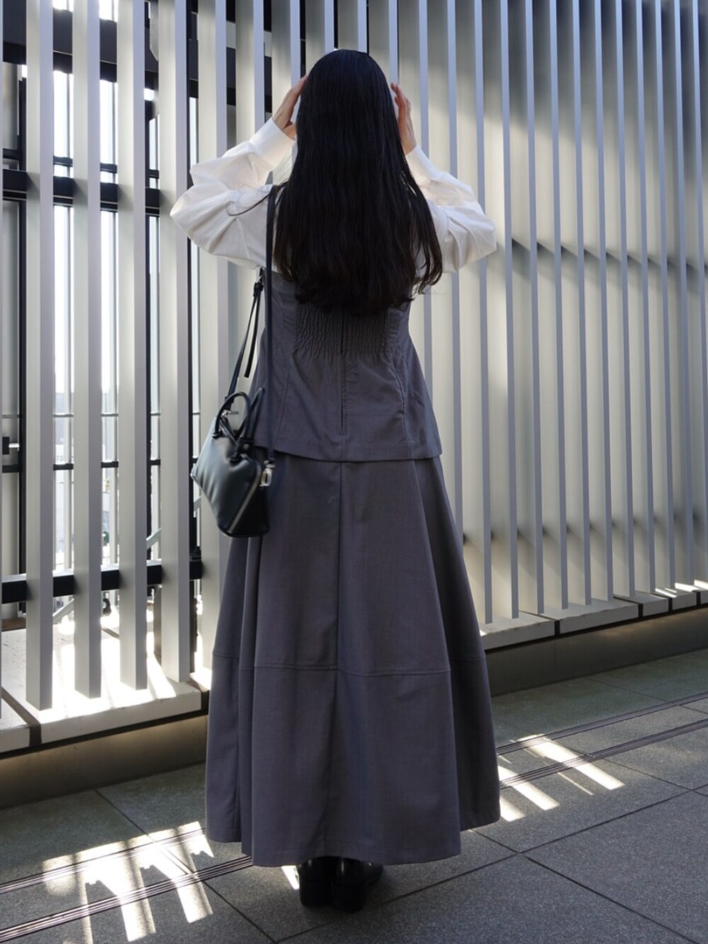 ブラック系のボストンバッグ、グレー系のワンピース、ブラック系のパンプスを着用したレディースの冬コーディネートの4枚目の写真
