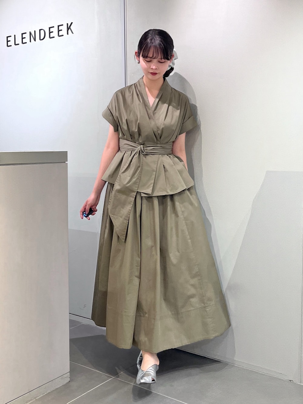 シルバー系のパンプス、グリーン系のワンピース、シルバー系のシュシュを着用したレディースの夏コーディネートの4枚目の写真