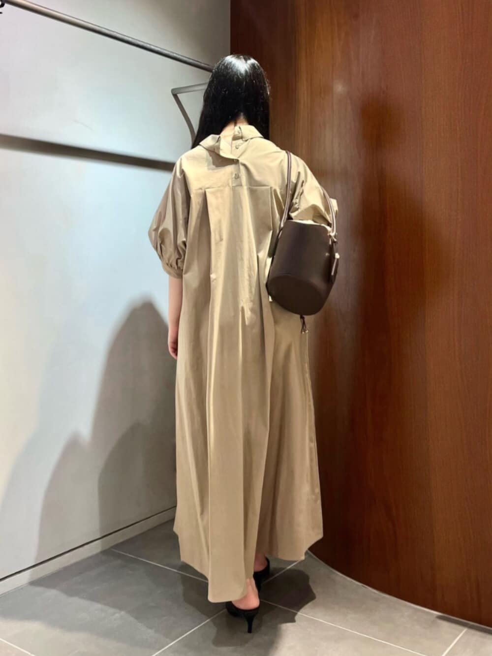 ブラック系のパンプス、ブラウン系のトートバッグ、ベージュ系のワンピースを着用したレディースの夏コーディネートの3枚目の写真