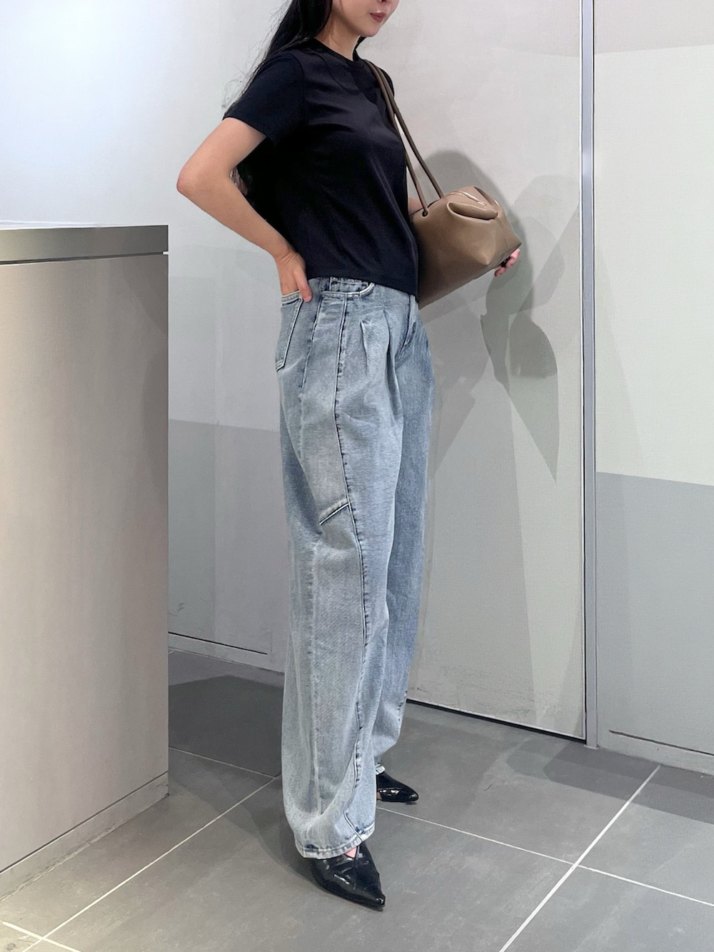 ブラック系のTシャツ/カットソー、ブルー系のデニムパンツ、ブラウン系のボストンバッグを着用したレディースの夏コーディネートの2枚目の写真