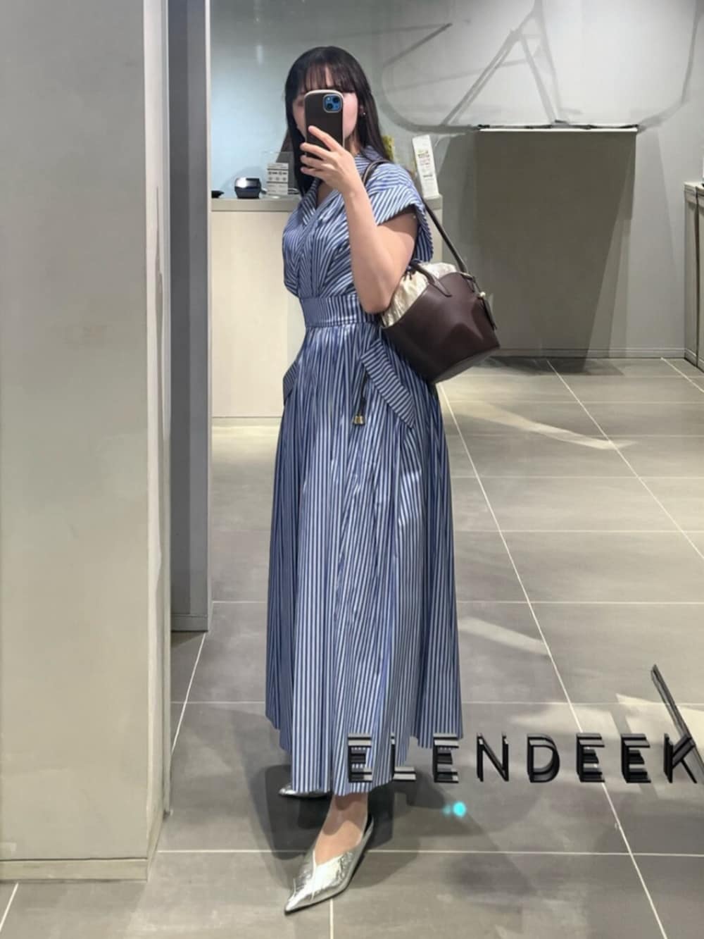 シルバー系のパンプス、その他のワンピース、ブラウン系のトートバッグを着用したレディースの春コーディネートの2枚目の写真