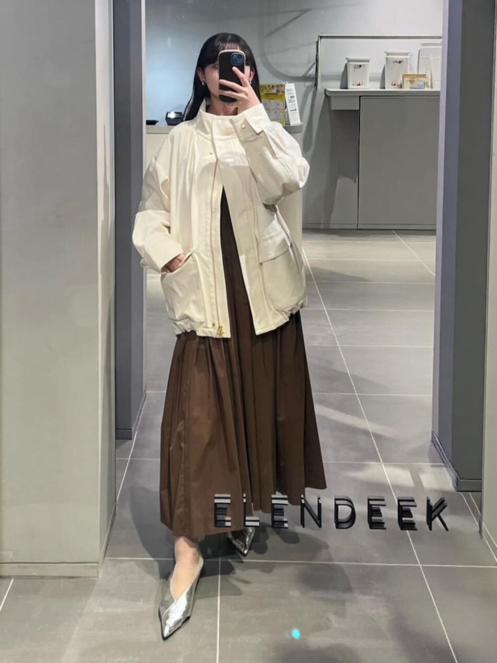 シルバー系のパンプス、ブラウン系のワンピース、グリーン系のトートバッグを着用したレディースの春コーディネートの5枚目の写真