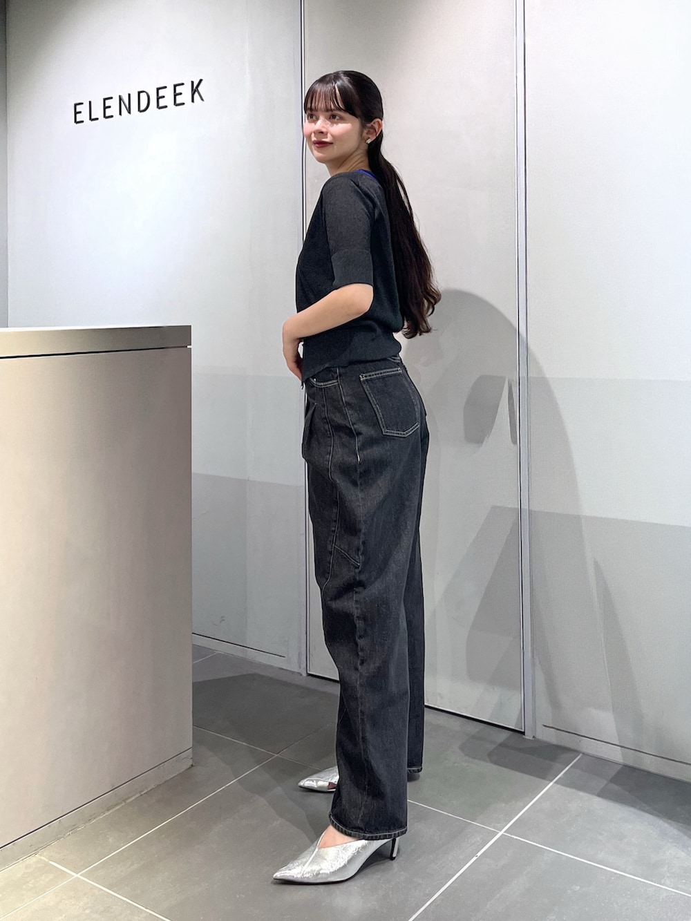 グレー系のニット/セーター、ブラック系のデニムパンツ、シルバー系のパンプスを着用したレディースの夏コーディネートの4枚目の写真