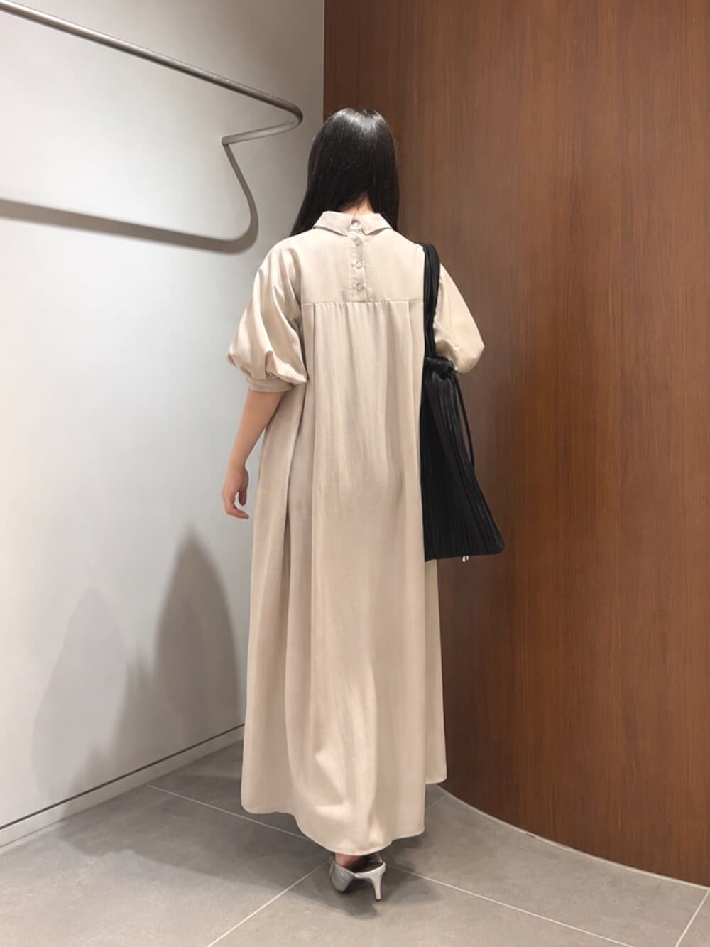 シルバー系のパンプス、ベージュ系のワンピース、ブラック系のトートバッグを着用したレディースの夏コーディネートの4枚目の写真