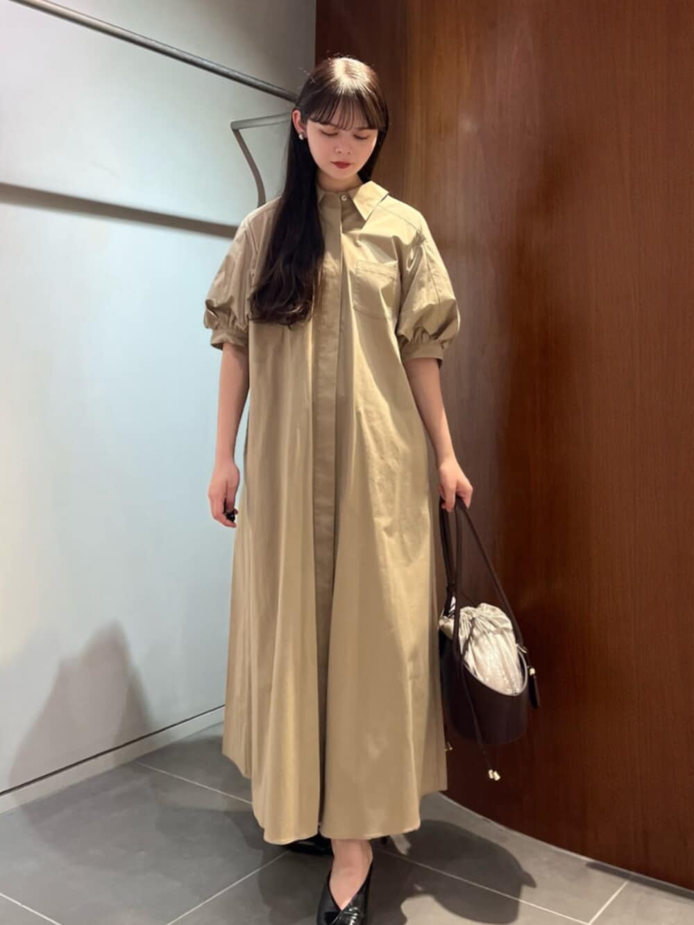 ブラック系のパンプス、ブラウン系のトートバッグ、ベージュ系のワンピースを着用したレディースの夏コーディネートの5枚目の写真
