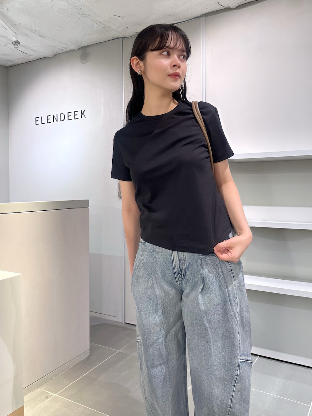 ブラック系のTシャツ/カットソー、ブルー系のデニムパンツ、ブラウン系のボストンバッグを着用したレディースの夏コーディネートの5枚目の写真
