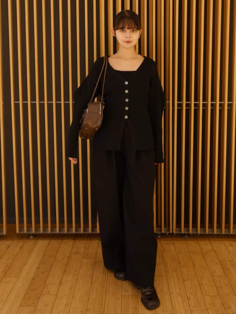 ブラック系のカーディガン/ボレロ、ブラック系のその他パンツ、ブラウン系のボストンバッグを着用したレディースの秋コーディネートの4枚目の写真