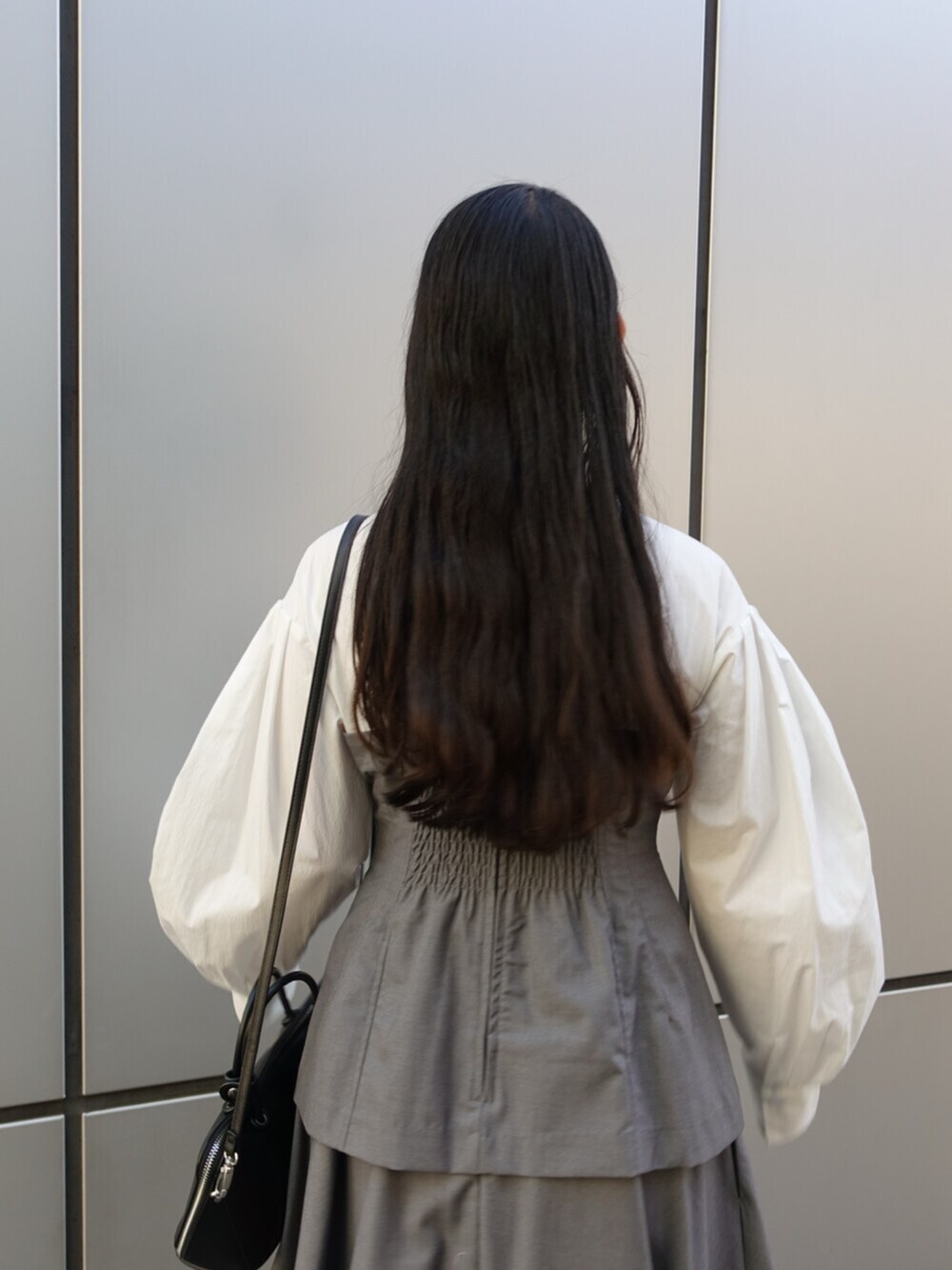ブラック系のボストンバッグ、グレー系のワンピース、ブラック系のパンプスを着用したレディースの冬コーディネートの7枚目の写真