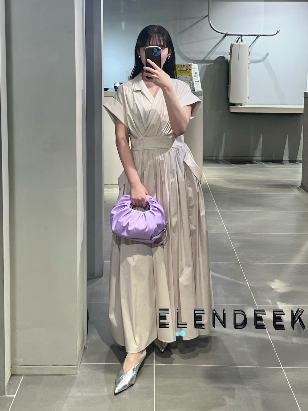 ベージュ系のワンピース、パープル系のハンドバッグ、シルバー系のパンプスを着用したレディースの春コーディネートの4枚目の写真