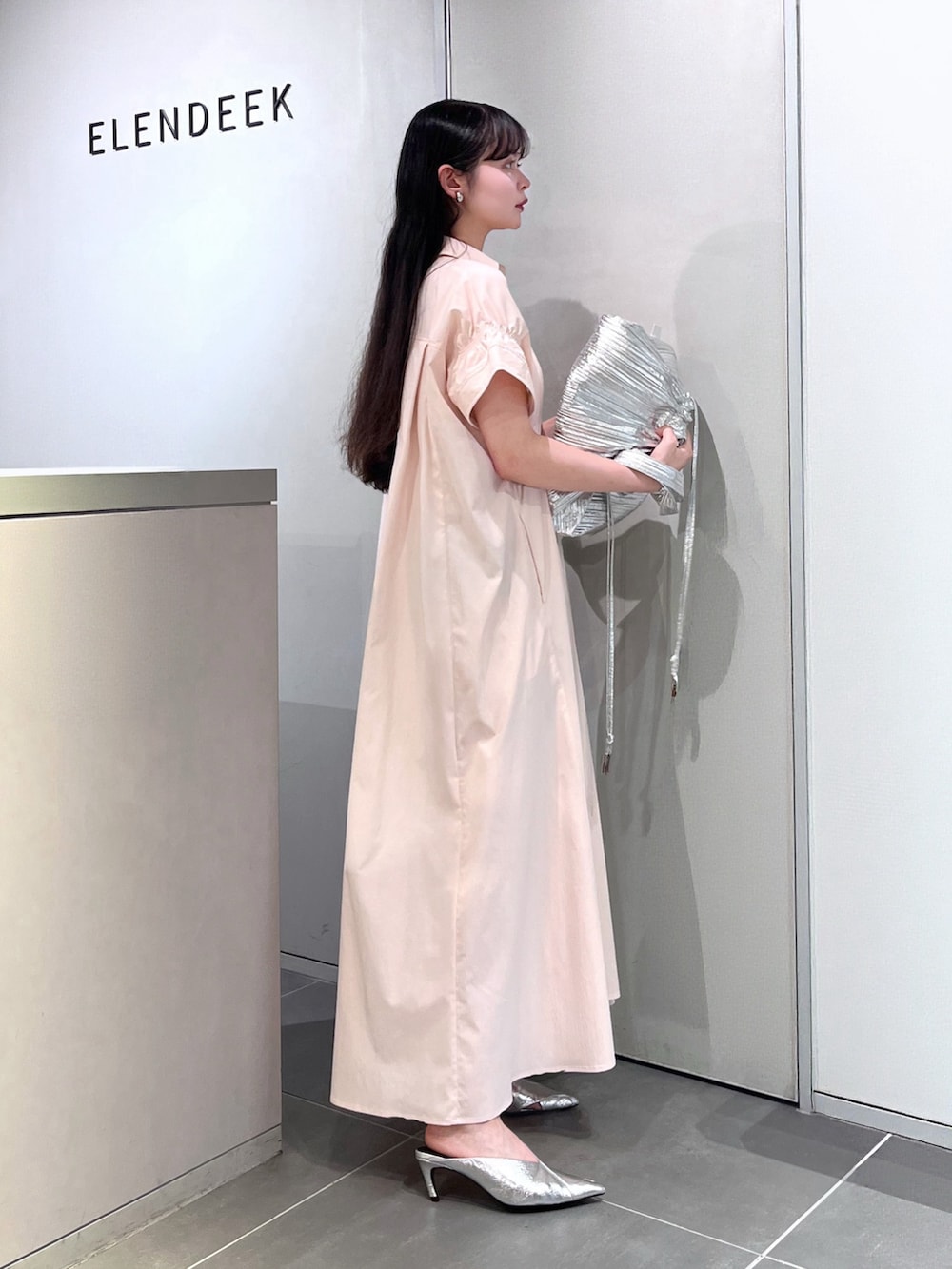 シルバー系のトートバッグ、シルバー系のパンプス、ピンク系のワンピースを着用したレディースの夏コーディネートの2枚目の写真