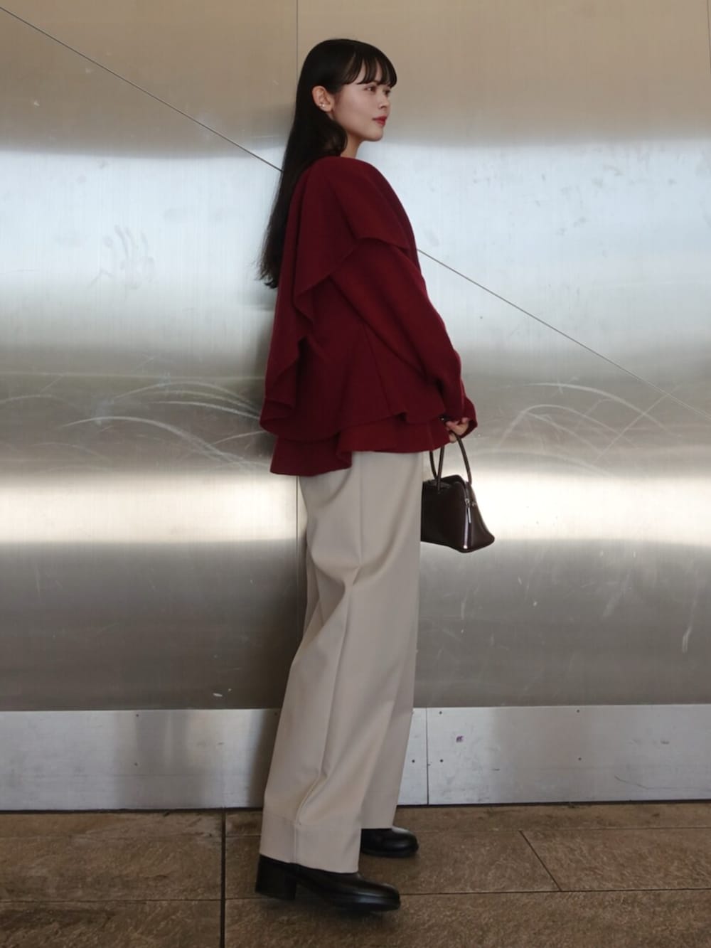 レッド系のニット/セーター、ホワイト系のその他パンツ、ブラック系のボストンバッグを着用したレディースの冬コーディネートの2枚目の写真