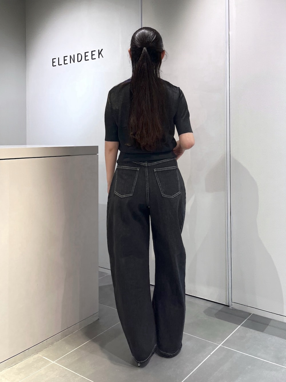 グレー系のニット/セーター、ブラック系のデニムパンツ、シルバー系のパンプスを着用したレディースの夏コーディネートの3枚目の写真