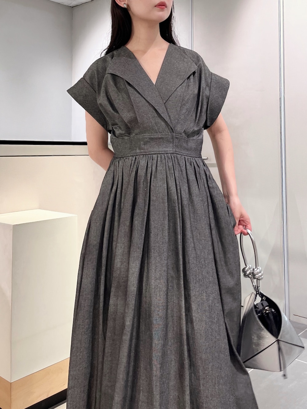 グレー系のワンピース、シルバー系のハンドバッグ、シルバー系のパンプスを着用したレディースの夏コーディネートの5枚目の写真