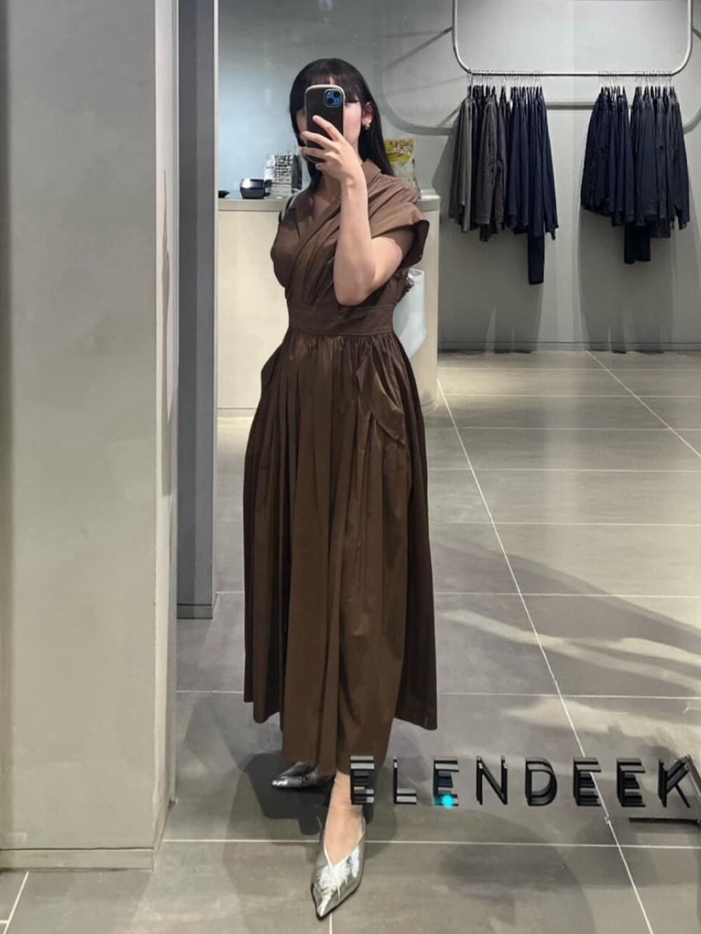 シルバー系のパンプス、ブラウン系のワンピース、グリーン系のトートバッグを着用したレディースの春コーディネートの2枚目の写真