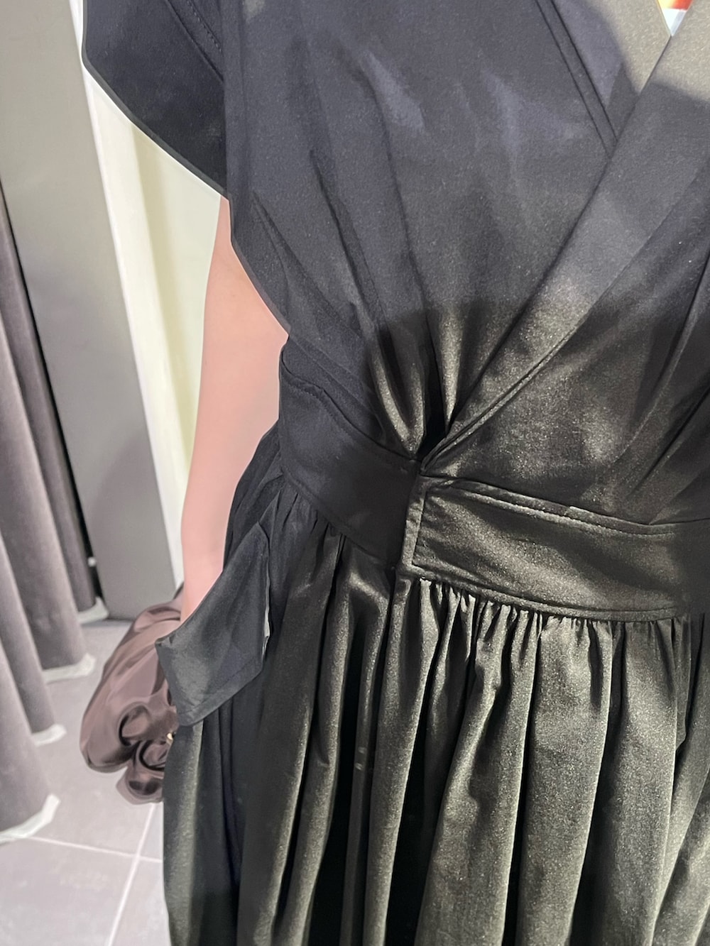 ブラック系のワンピース、ブラウン系のハンドバッグ、シルバー系のパンプスを着用したレディースの春コーディネートの5枚目の写真