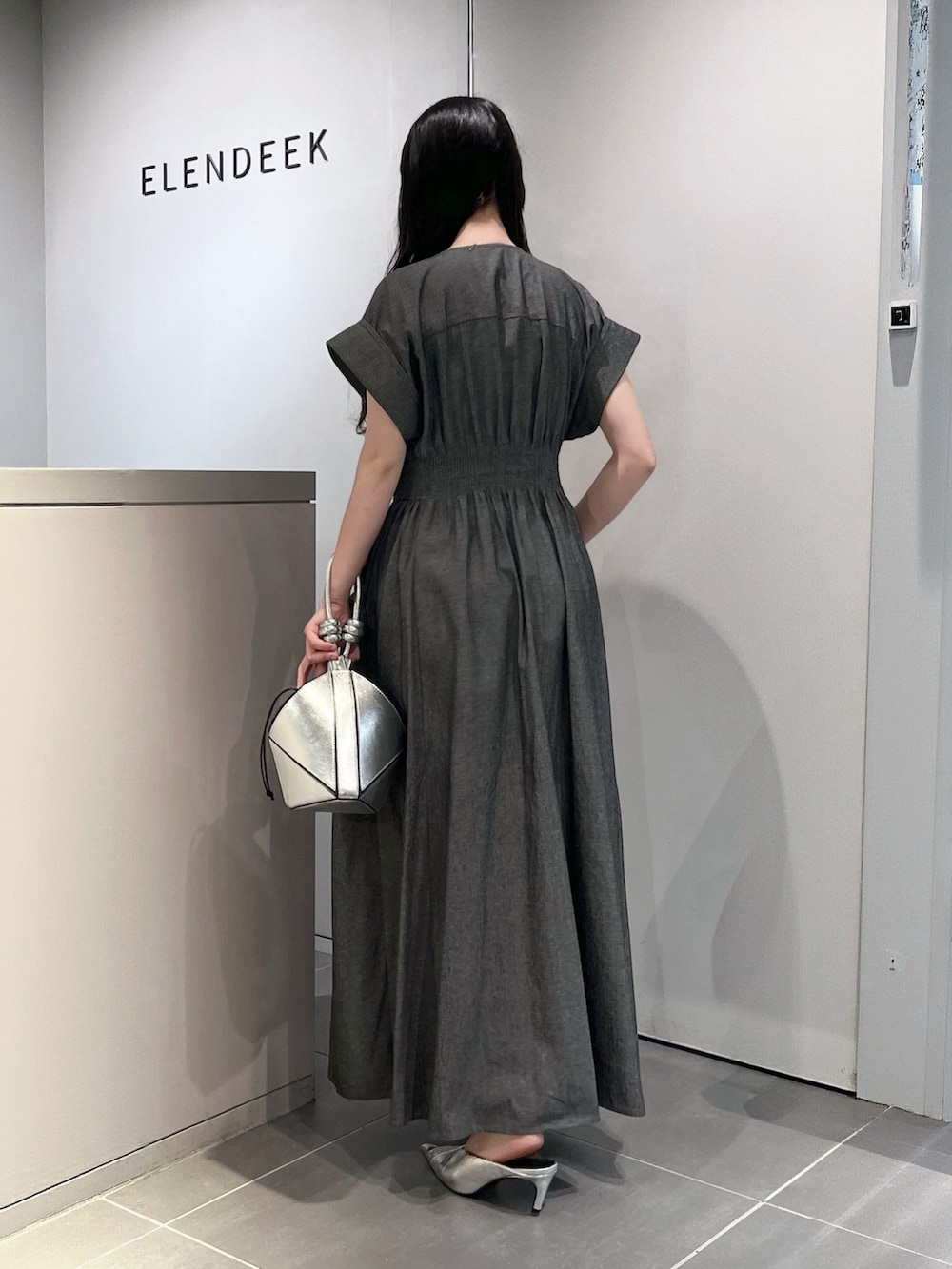 グレー系のワンピース、シルバー系のハンドバッグ、シルバー系のパンプスを着用したレディースの夏コーディネートの3枚目の写真