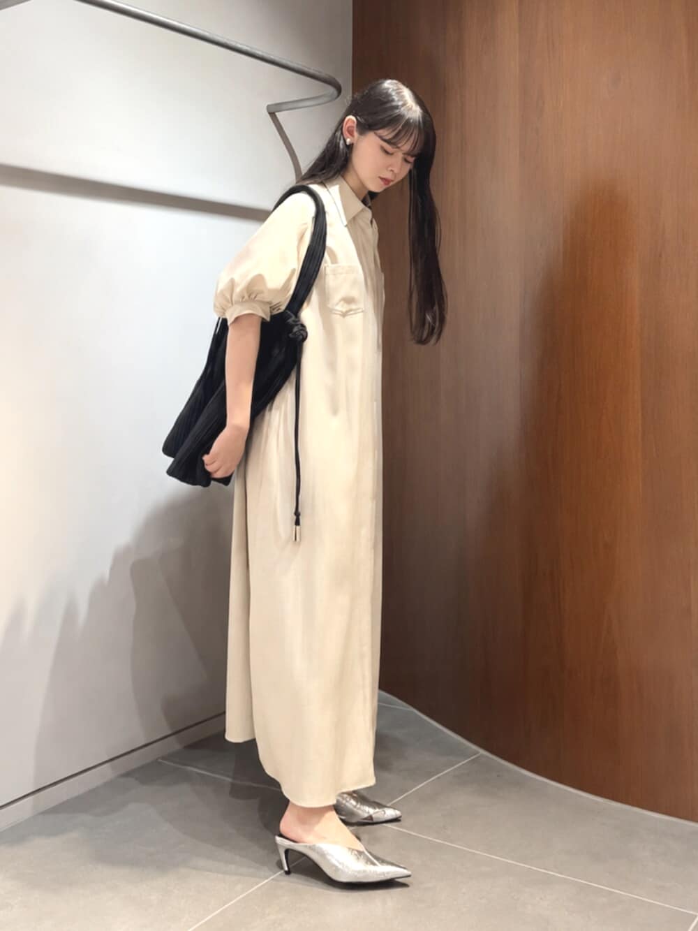 シルバー系のパンプス、ベージュ系のワンピース、ブラック系のトートバッグを着用したレディースの夏コーディネートの3枚目の写真