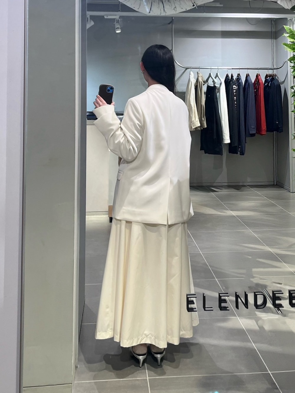 ホワイト系のノーカラージャケット、シルバー系のパンプス、ホワイト系のワンピースを着用したレディースの春コーディネートの3枚目の写真