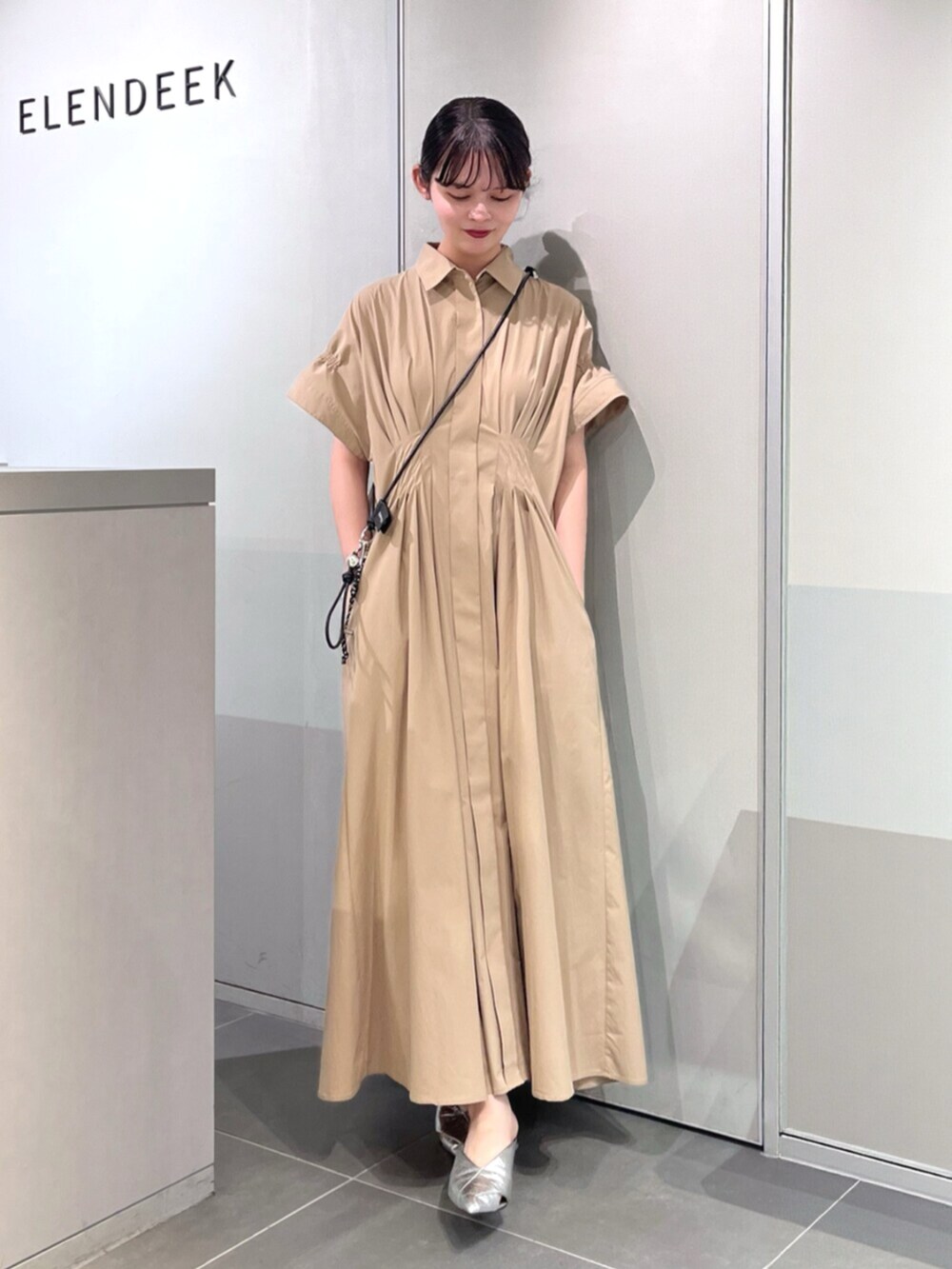 シルバー系のパンプス、ベージュ系のワンピース、ブラック系のスマホグッズを着用したレディースの夏コーディネートの5枚目の写真