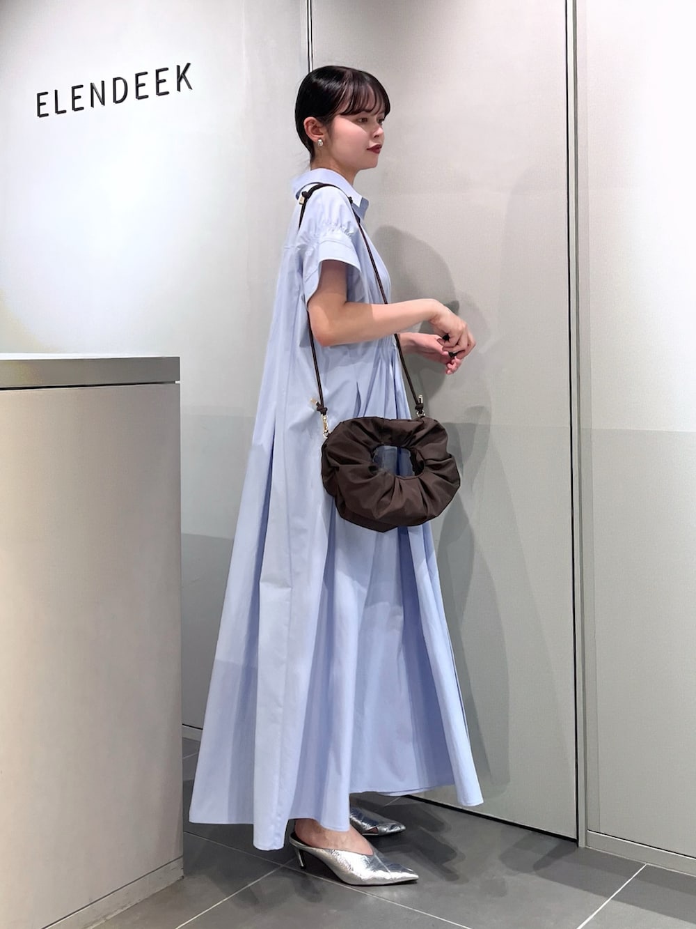 シルバー系のパンプス、ブラウン系のハンドバッグ、ブルー系のワンピースを着用したレディースの夏コーディネートの2枚目の写真