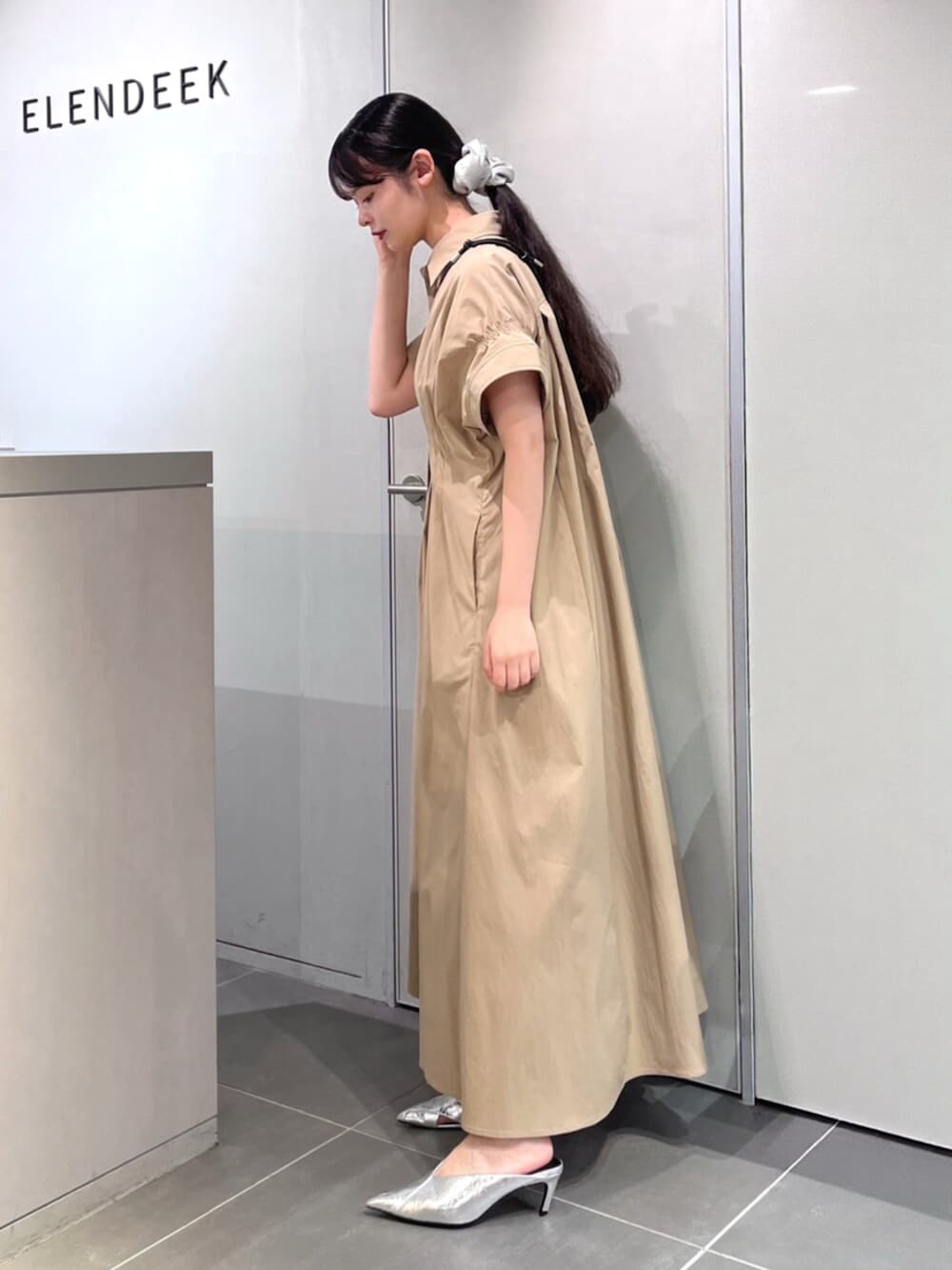 シルバー系のパンプス、ベージュ系のワンピース、ブラック系のスマホグッズを着用したレディースの夏コーディネートの3枚目の写真