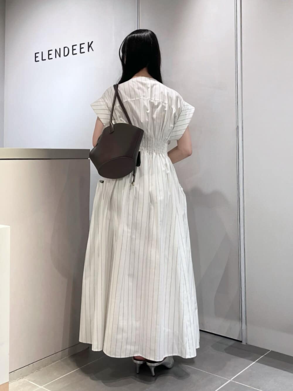 シルバー系のパンプス、ブラウン系のトートバッグ、その他のワンピースを着用したレディースの夏コーディネートの3枚目の写真