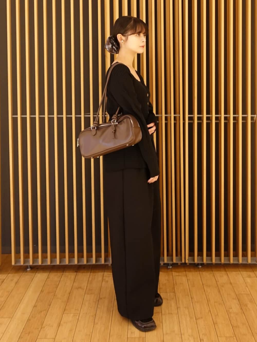 ブラック系のカーディガン/ボレロ、ブラック系のその他パンツ、ブラウン系のボストンバッグを着用したレディースの秋コーディネートの2枚目の写真