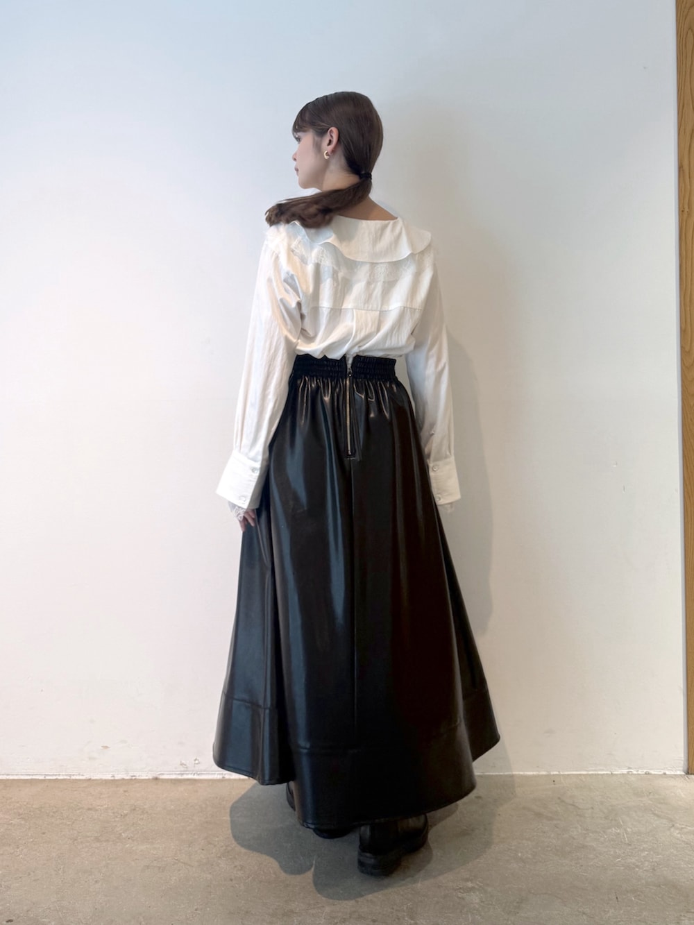 ホワイト系のシャツ/ブラウス、ブラック系のスカート、ブラック系のブーツを着用したレディースの秋コーディネートの3枚目の写真