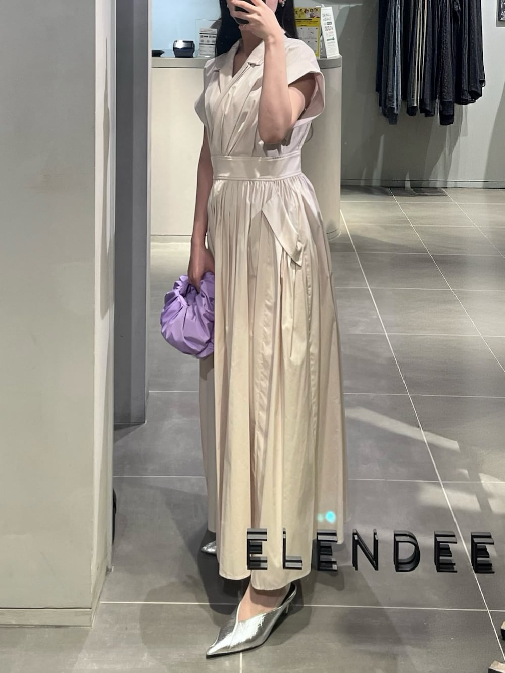 ベージュ系のワンピース、パープル系のハンドバッグ、シルバー系のパンプスを着用したレディースの春コーディネートの2枚目の写真