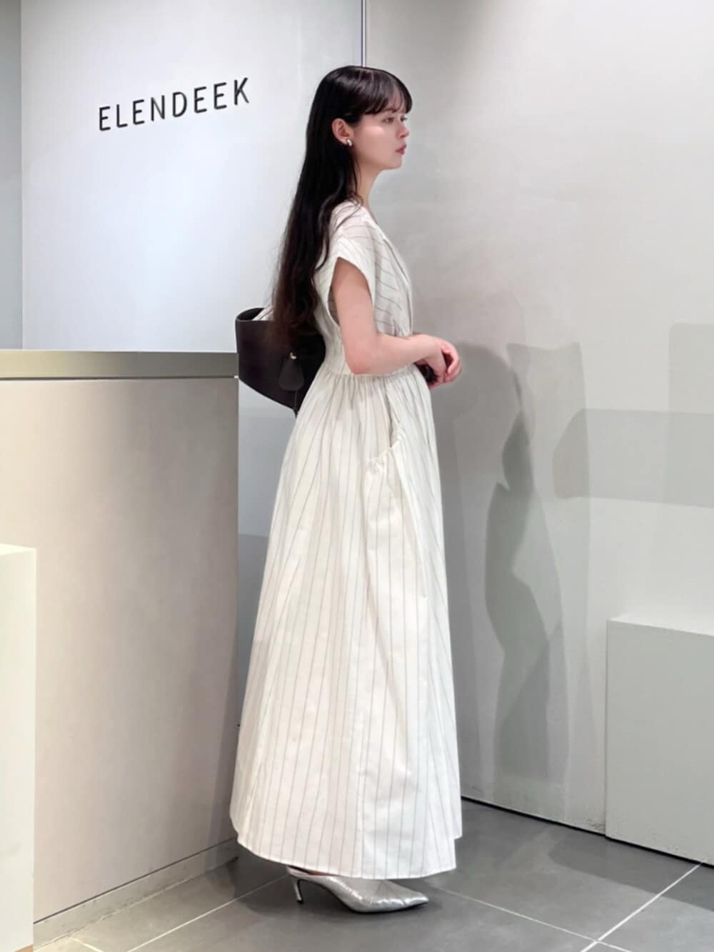 シルバー系のパンプス、ブラウン系のトートバッグ、その他のワンピースを着用したレディースの夏コーディネートの2枚目の写真