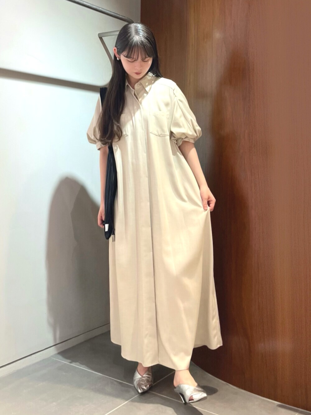シルバー系のパンプス、ベージュ系のワンピース、ブラック系のトートバッグを着用したレディースの夏コーディネートの2枚目の写真