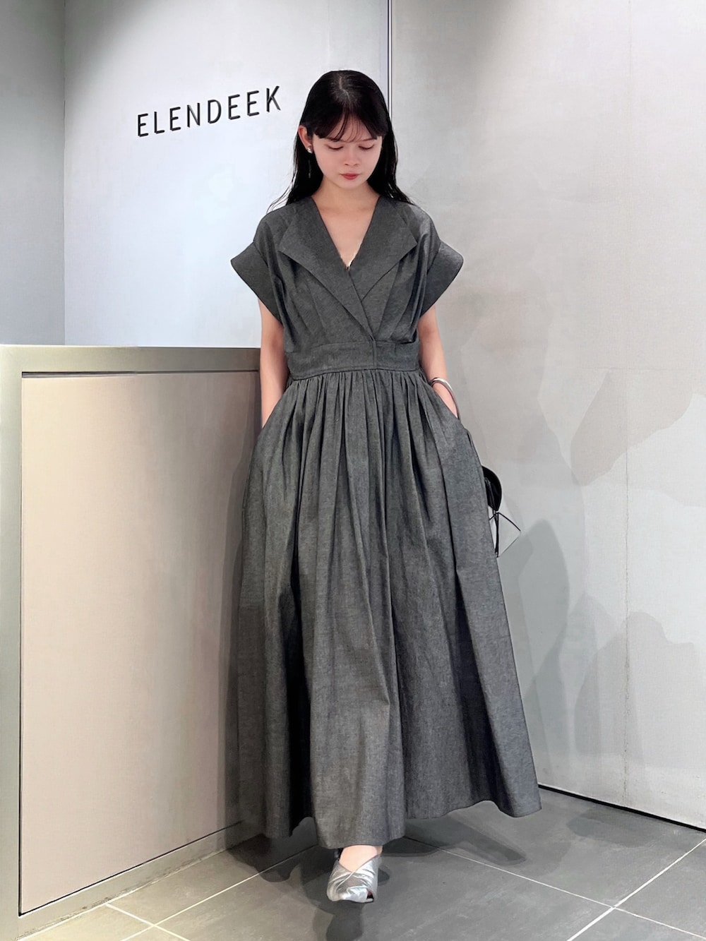 グレー系のワンピース、シルバー系のハンドバッグ、シルバー系のパンプスを着用したレディースの夏コーディネートの4枚目の写真