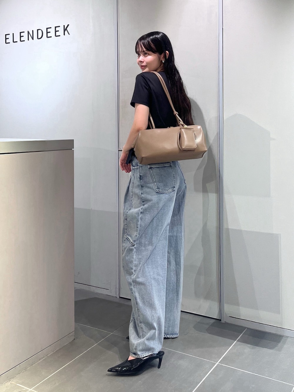 ブラック系のTシャツ/カットソー、ブルー系のデニムパンツ、ブラウン系のボストンバッグを着用したレディースの夏コーディネートの4枚目の写真