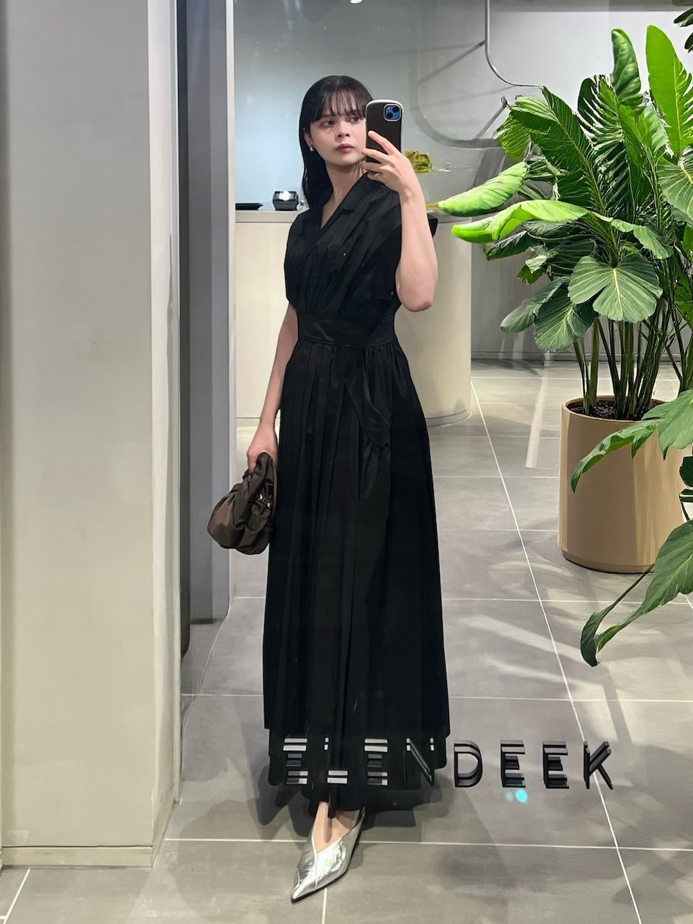 ブラック系のワンピース、ブラウン系のハンドバッグ、シルバー系のパンプスを着用したレディースの春コーディネートの2枚目の写真