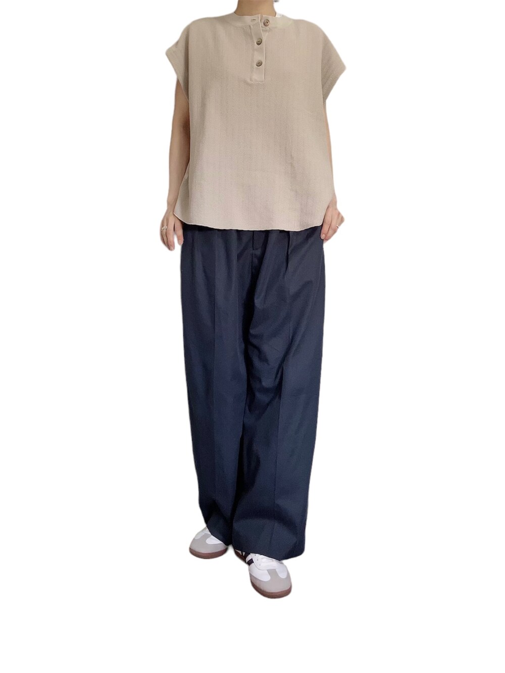 ベージュ系のニット/セーター、ブルー系のスラックスを着用したレディースの夏コーディネートの2枚目の写真