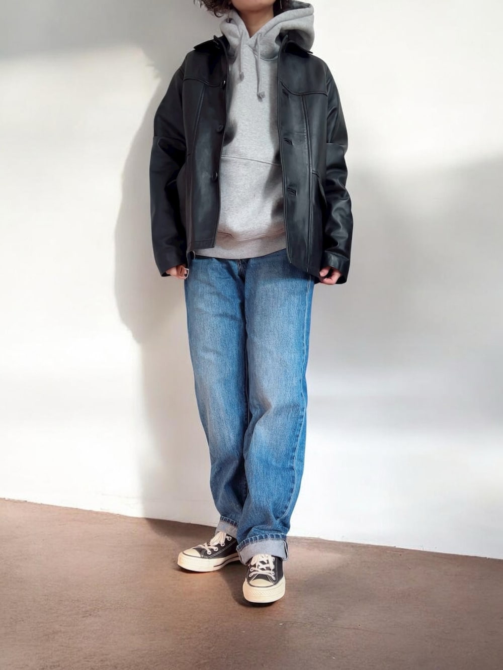 グレー系のパーカー、ブラック系のカバーオール、ブルー系のデニムパンツを着用したレディースの冬コーディネートの2枚目の写真