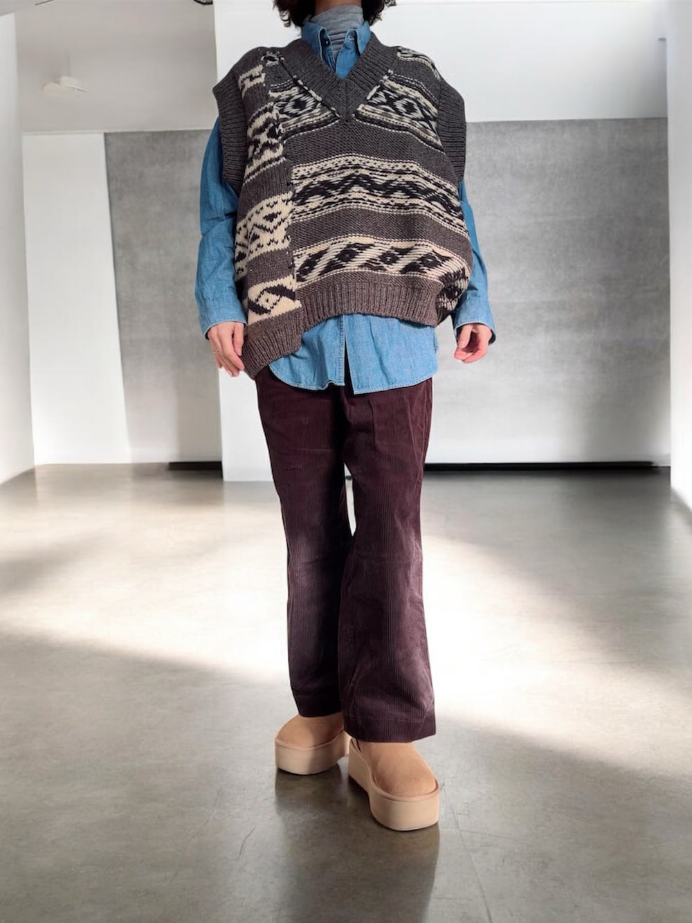 ベージュ系のブルゾン、グレー系のベスト、ブラウン系のパンツを着用したレディースの冬コーディネートの2枚目の写真