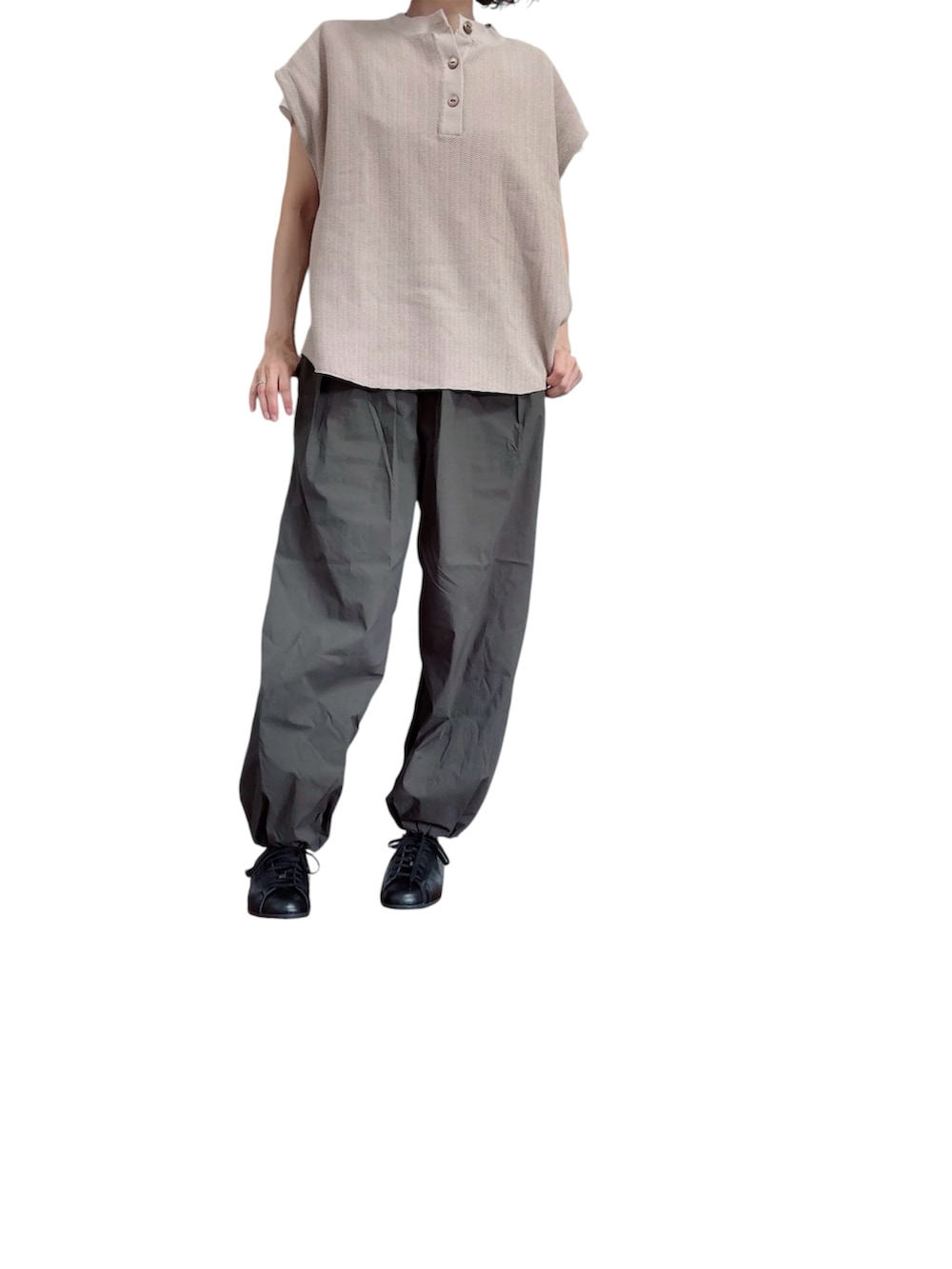 ベージュ系のニット/セーター、グレー系のパンツ、ブラック系のスニーカーを着用したレディースの夏コーディネートの2枚目の写真