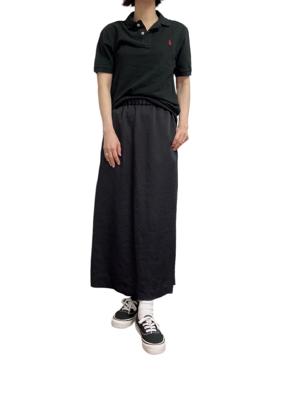 ブラック系のポロシャツ、ブラック系のスカート、ブラック系のスニーカーを着用したレディースの夏コーディネートの2枚目の写真