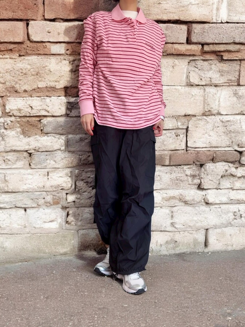 ピンク系のポロシャツ、ブラック系のパンツ、シルバー系のスニーカーを着用したレディースの冬コーディネートの2枚目の写真