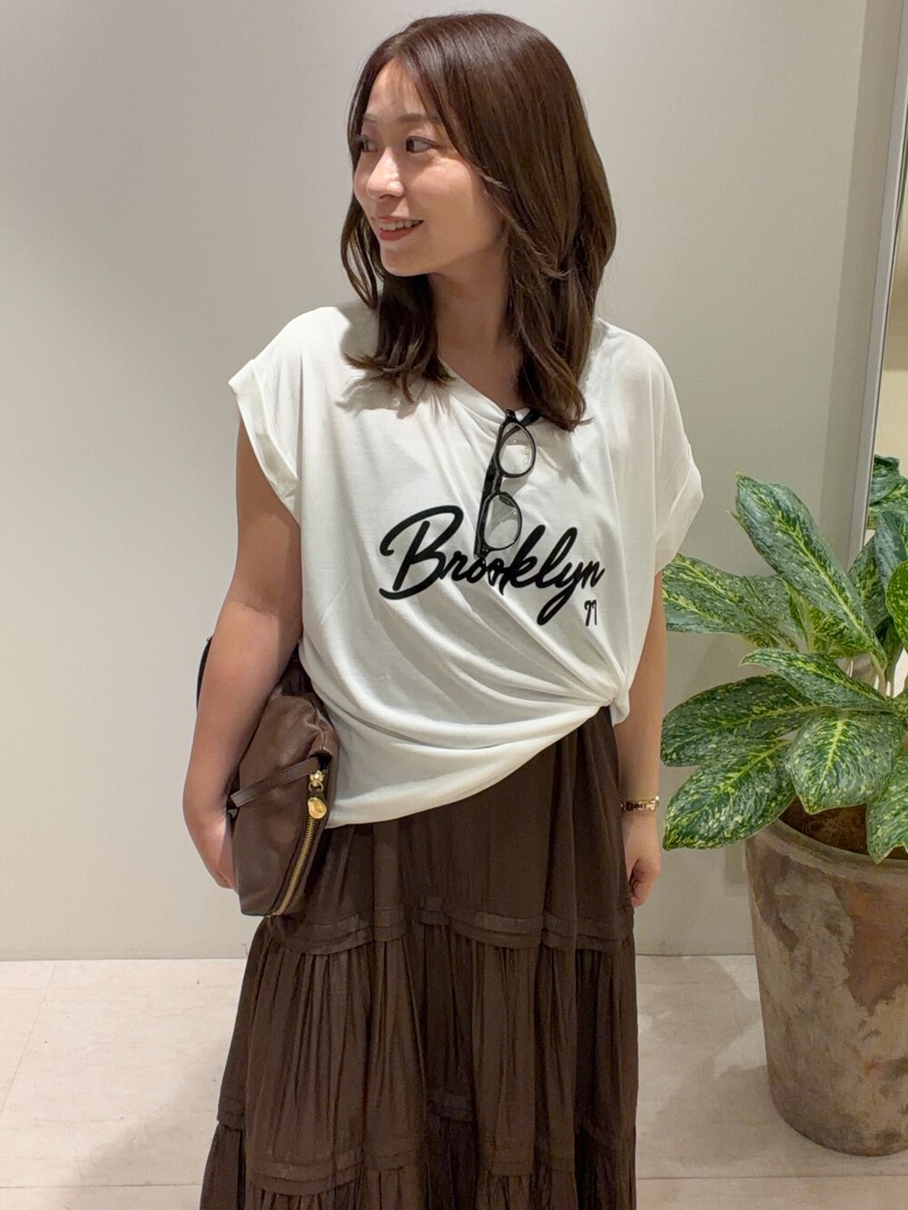 ブラウン系のワンピース、ホワイト系のTシャツ/カットソー、ブラウン系のショルダーバッグを着用したレディースの夏コーディネートの2枚目の写真