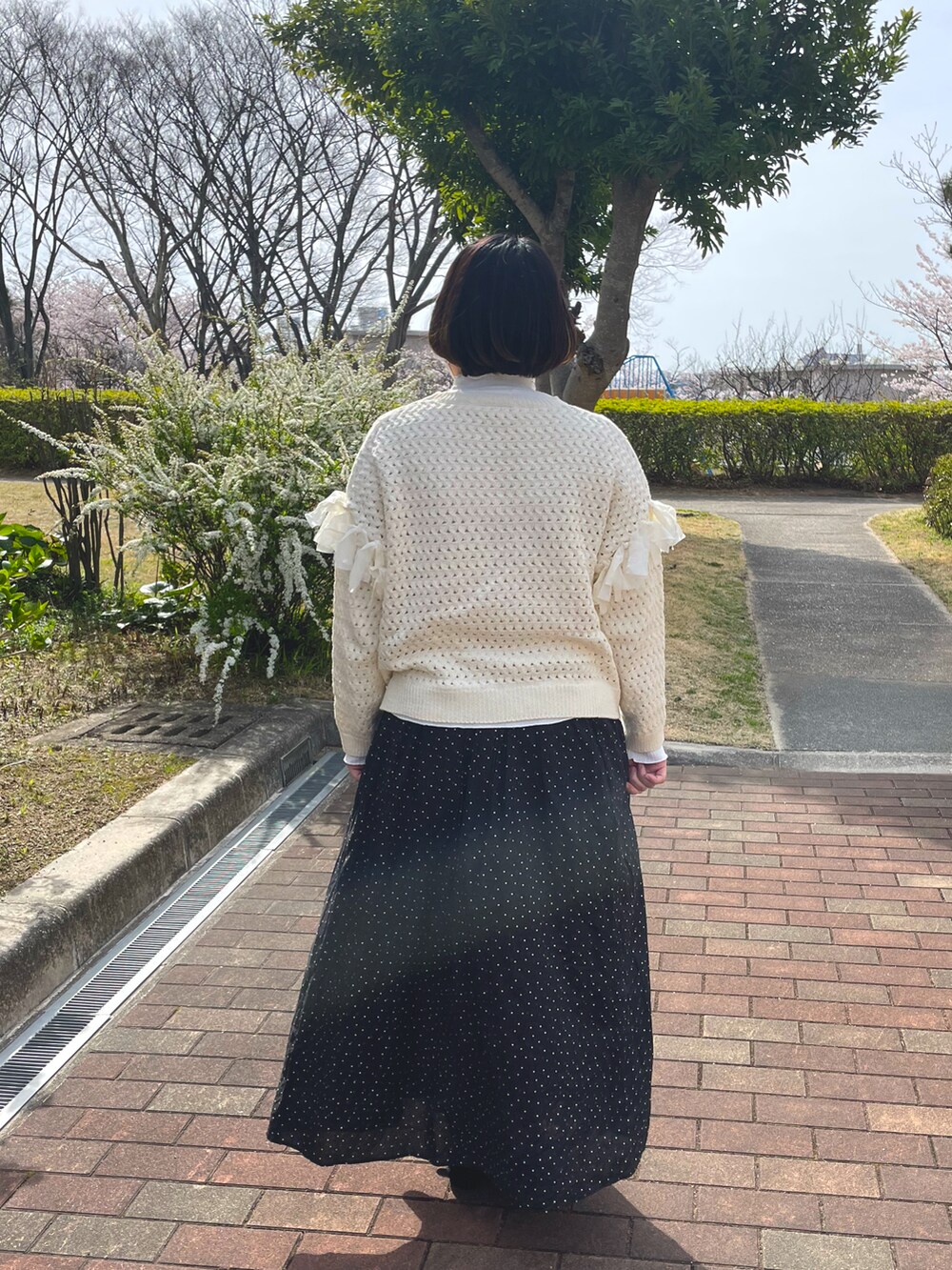 ホワイト系のニット/セーター、ホワイト系のTシャツ/カットソー、ブラック系のスカートを着用したレディースの春コーディネートの3枚目の写真